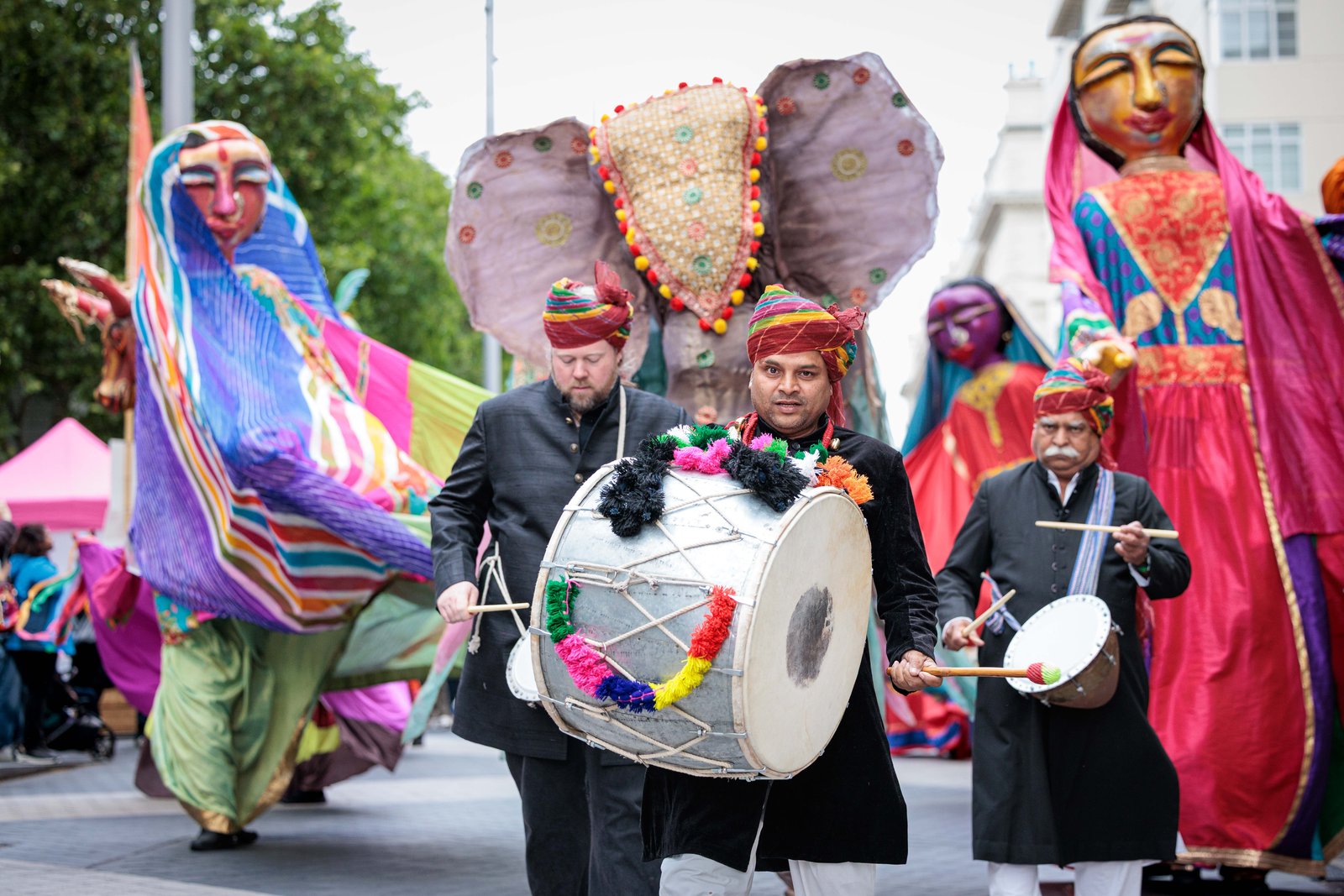 Parade with drummers and giant puppets Performers playing drums lead a vibrant street procession featuring giant puppets, colourful costumes and an elephant figure during Serendipity Arts' Giants on the Move at the Great Exhibition Road Festival.