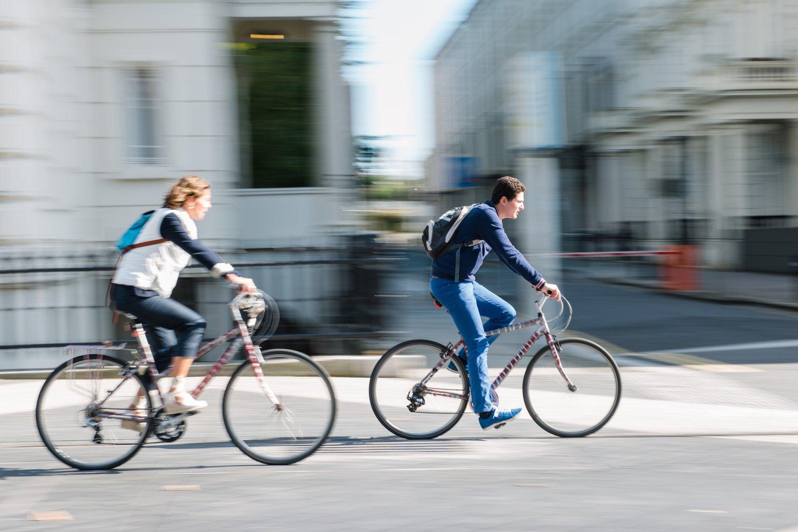 Two cyclists Two cyclists riding along a city street in South Kensington, with motion blur conveying movement and historic buildings in the background